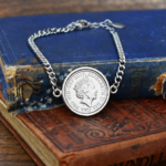 Crowned Elizabeth II portrait dated 2017 in a silver-tone bezel on a chain bracelet, propped against worn books