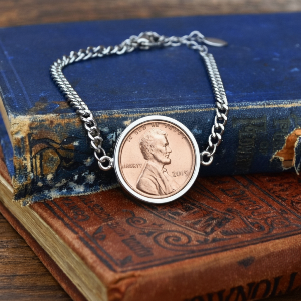 Coin bracelet with a 2019 US one cent piece in a silver-coloured surround, laid over old blue and red books