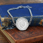 Seven-sided 2020 twenty pence set in silver-coloured metal on a curb chain bracelet, laid on old book spines