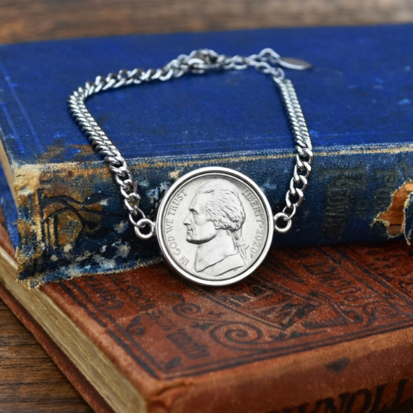 2020 US nickel in a silver-coloured bezel on a curb chain bracelet, resting on old blue and tan books