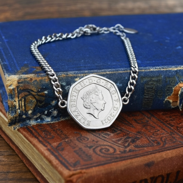 2021 twenty pence coin bracelet, silver-coloured setting and curb-link chain, propped on two worn hardbacks